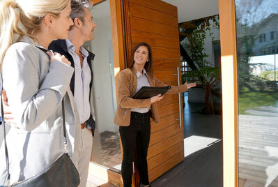 An estate agent welcoming two people into a house