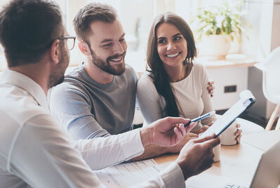 Three people having a meeting while someone points at a clipboard with a pen