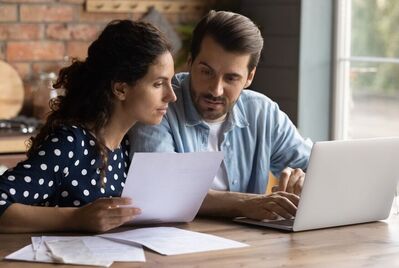 A couple sat in front of a laptop