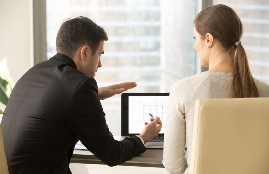 An estate agent pointing at a screen with someone watching him