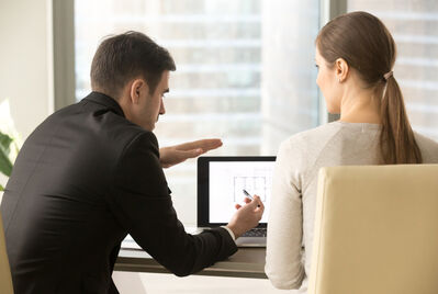 An estate agent pointing at a screen with someone watching him