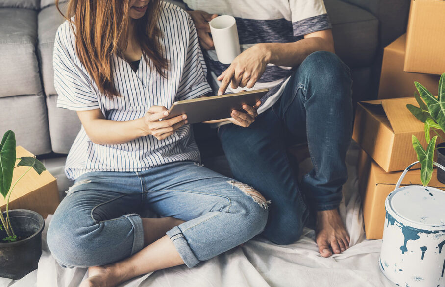 A couple sitting on the floor looking at a tablet