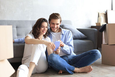 Two people sitting on the floor looking at a phone