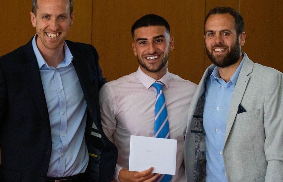 Three people standing together holding an award