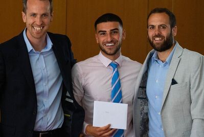 Three people standing together holding an award