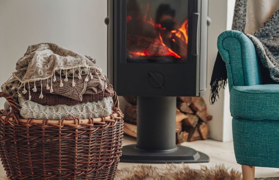 A basket of blankets and an armchair in front of a fire