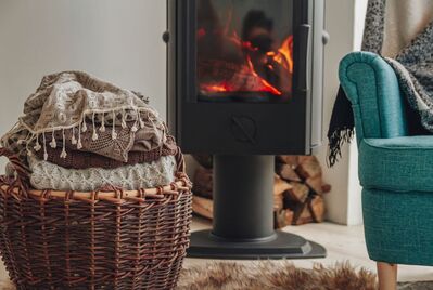 A basket of blankets and an armchair in front of a fire