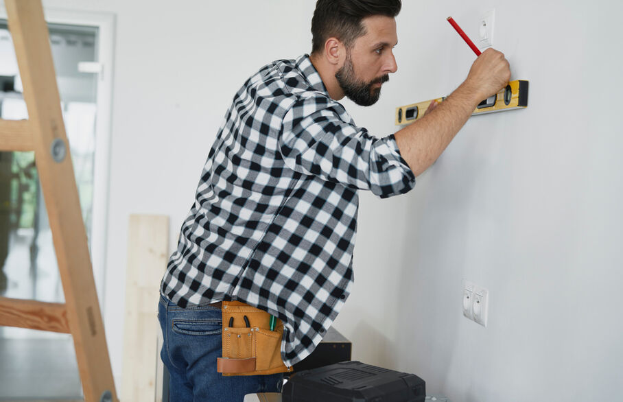 Someone with a spirit leveler measuring a wall 