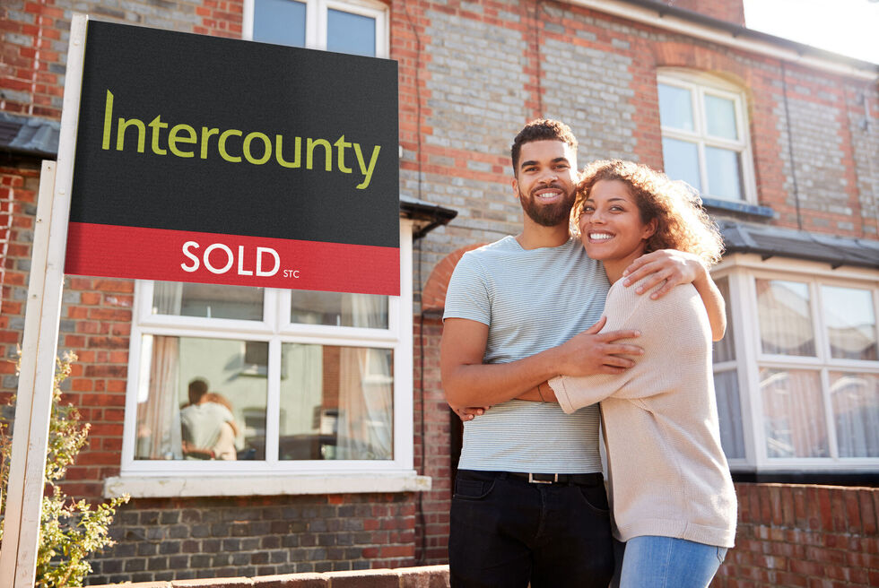 Happy couple with an Intercounty sold board
