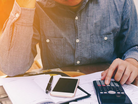 Man using calculator, with mobile in front of him