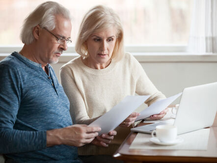 Older couple sat at table looking at bills 
