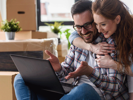 Happy couple checking the status of their conveyancing on laptop 