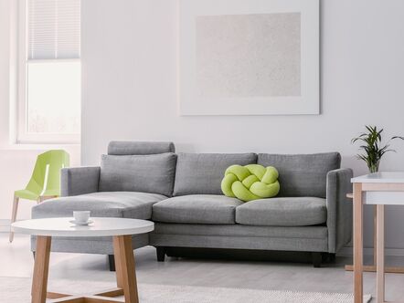 Lime green knot pillow on grey corner couch